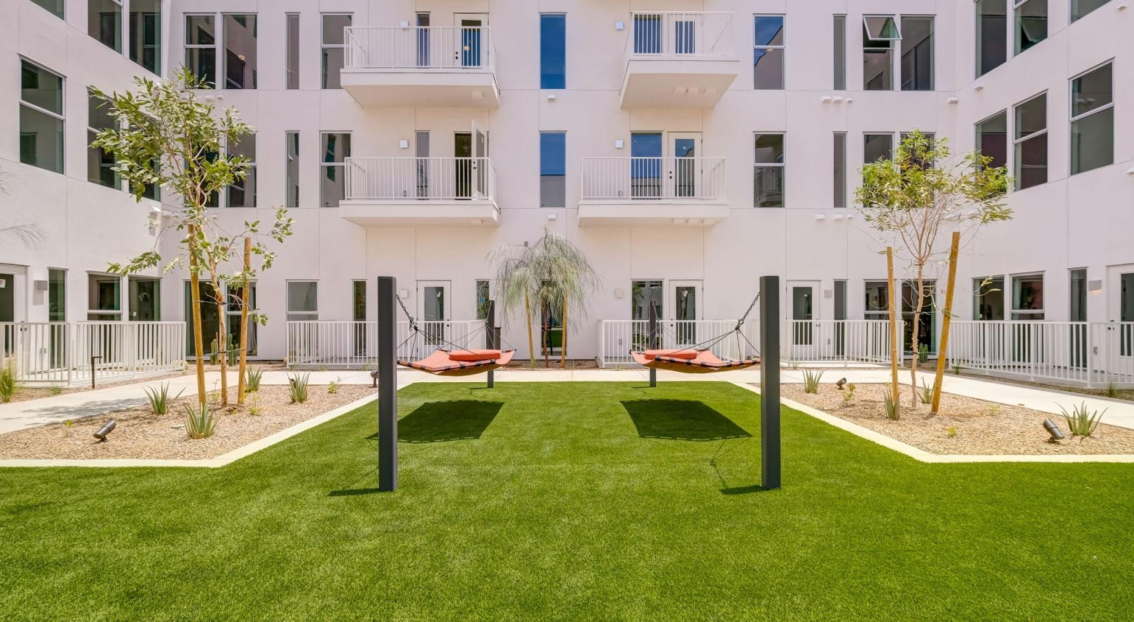 State-of-the-art amenities a building with a lawn and hammocks