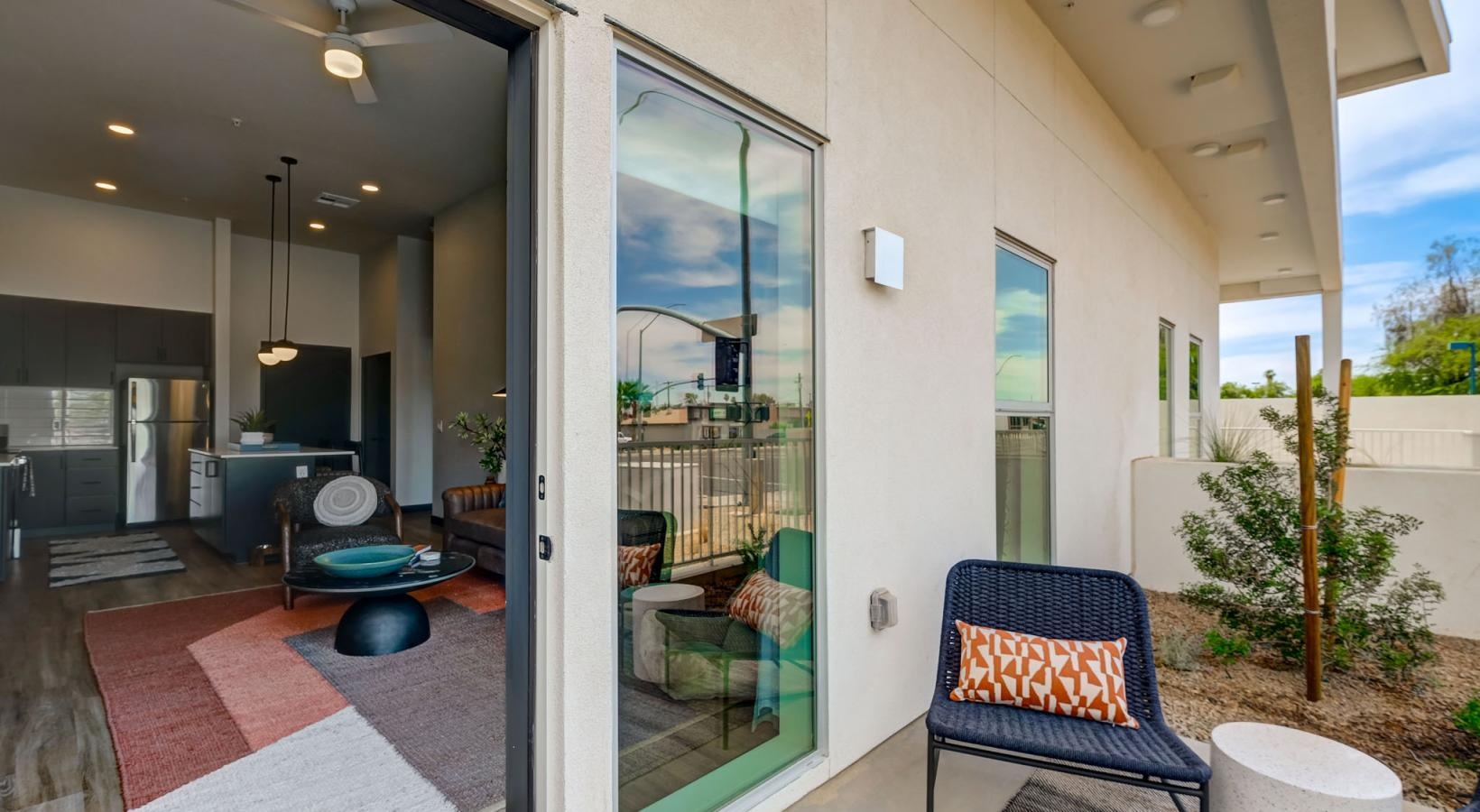 Generous balconies a room with a glass door and a patio with chairs and a rug