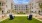 a lawn with chairs and trees in front of a building