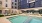 a pool with chairs and umbrellas by a building
