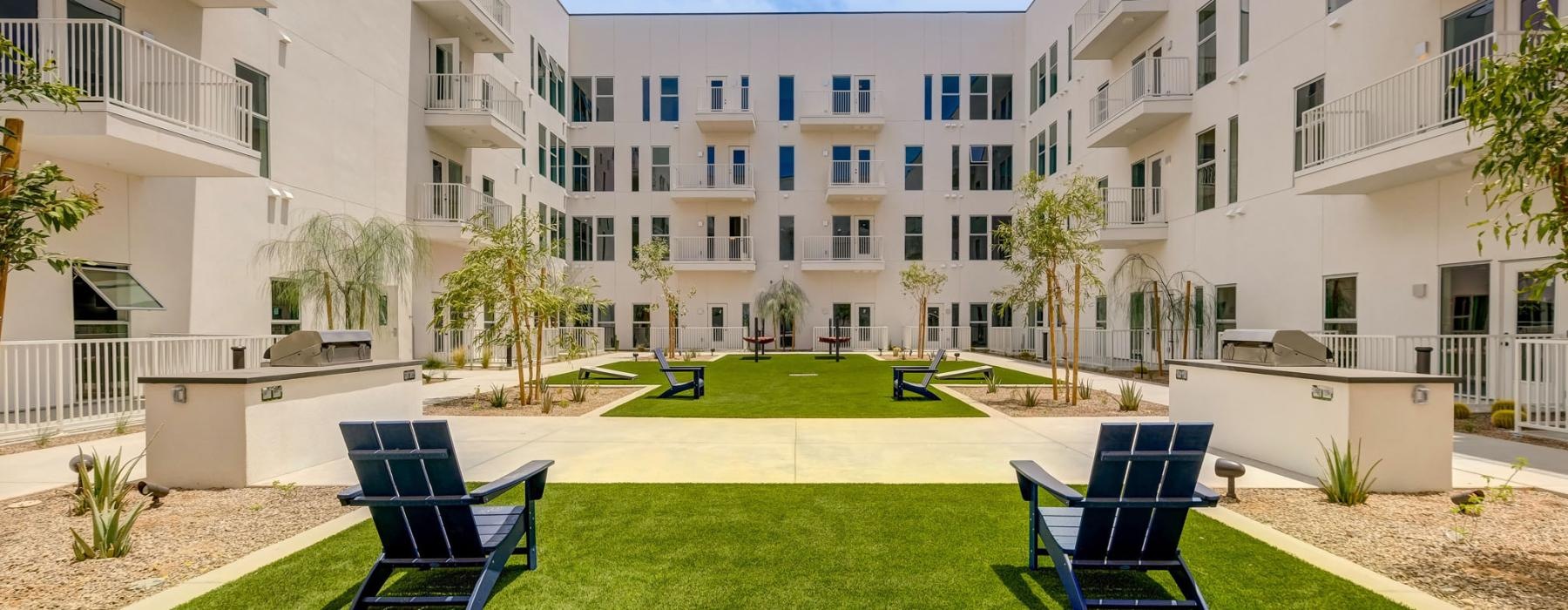 a lawn with chairs and trees in front of a building